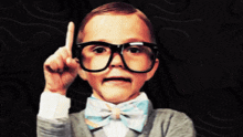 a young boy wearing glasses and a bow tie is pointing up