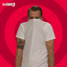 a man with a tattoo on his arm is covering his face in front of a red background with swr3 written on it