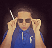 a man wearing sunglasses and a blue shirt with the letter f on the front
