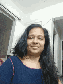 a woman in a blue shirt is smiling for the camera