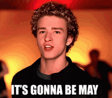 a young man with curly hair says " it 's gonna be may " in front of him