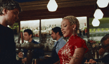 a woman in a red dress has a tattoo on her arm that says i love you