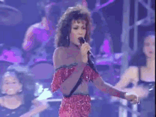 a woman in a red dress is singing into a microphone on stage