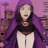 a woman in a raven costume is standing in front of a cat tree with a purple background