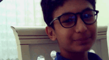a young boy wearing glasses and a blue shirt smiles