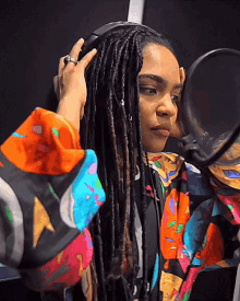 a woman with dreadlocks is adjusting her headphones