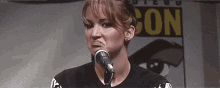 a woman is making a funny face while speaking into a microphone at a comic con .