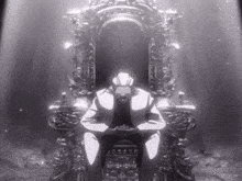 a man in a suit sits on a throne in a dark room