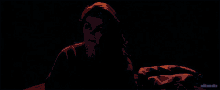 a woman in a blue shirt is sitting in a dark room with the words editsmike below her