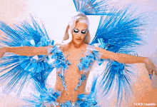 a drag queen is wearing a blue and white outfit with wings