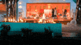 a group of people standing in a living room with a fire pit in the middle