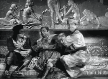a black and white photo of three men sitting in front of a sculpture