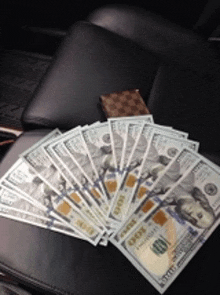 a fan of 100 dollar bills on a chair