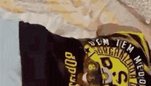 a person is laying on a bed with a black and yellow shirt on their head .