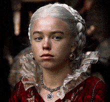 a woman with braided hair wearing a red dress and a necklace with a coin on it
