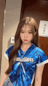 a girl in a blue guardians jersey stands in front of a door
