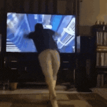 a person is dancing in front of a television .