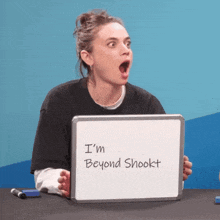 a woman is holding a whiteboard that says i 'm beyond shookt