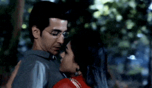 a man and a woman are hugging each other in a park .