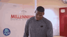 a man is standing in front of a millennium dance company wall