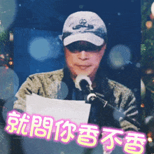 a man speaking into a microphone with chinese writing on the bottom right