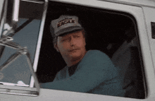 a man wearing a good year eagle hat looks out the window