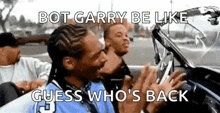 snoop dogg is sitting in the back seat of a car with a group of men behind him .