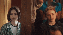 two girls are standing next to each other and one is wearing a plaid jacket