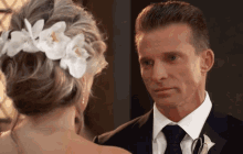 a man and woman are looking at each other and the woman has flowers in her hair