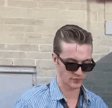 the man is wearing sunglasses and a striped shirt .