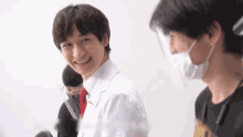 a man in a white lab coat is smiling while wearing a face shield