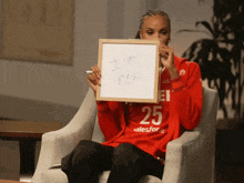 a woman sitting in a chair holding up a sign that says " i 'm new "