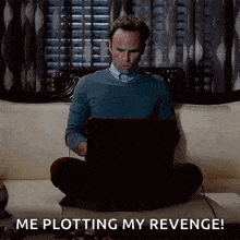 a man is sitting on a couch with his legs crossed using a laptop .