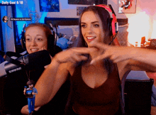 a woman wearing headphones stands next to another woman wearing headphones and a shure microphone