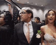 a man in a suit and tie stands next to a woman in a wedding dress