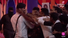 a group of people are hugging each other on a stage in front of a curtain .