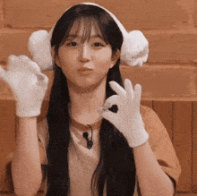 a woman wearing a headband and white gloves is giving an ok sign