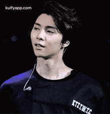 a young man wearing headphones and a black shirt is making a face .