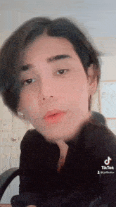 a close up of a person 's face with a black shirt and earrings .