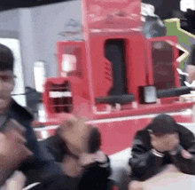 a group of people are sitting at a table in front of a red box .