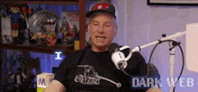 a man is sitting in front of a microphone wearing a black shirt that says creating