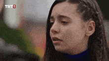 a close up of a girl 's face with a trt1 logo in the background