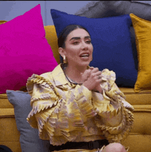 a woman sitting on a yellow couch with pillows
