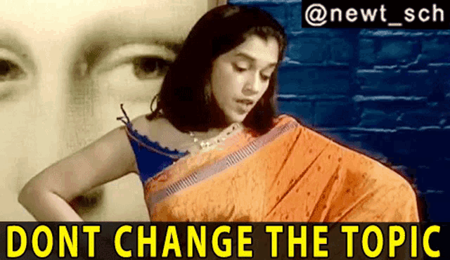 a woman in an orange saree is standing in front of a brick wall with the words 
