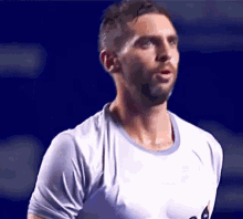 a man with a beard is wearing a white shirt and looking to the side .
