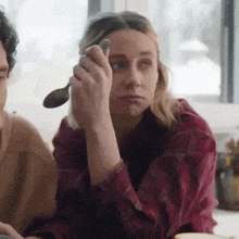 a woman in a plaid shirt is holding a spoon in her hand