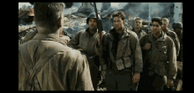 a group of soldiers are standing next to each other in front of a building .