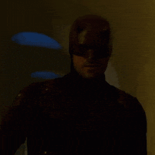 a man in a daredevil costume is standing in a dark room in a dark room .