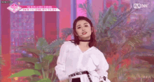 a woman in a white shirt is dancing on a stage in front of a microphone .