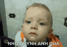 a baby is making a sad face and the words nho quynh anh qua are written on the bottom of the picture .